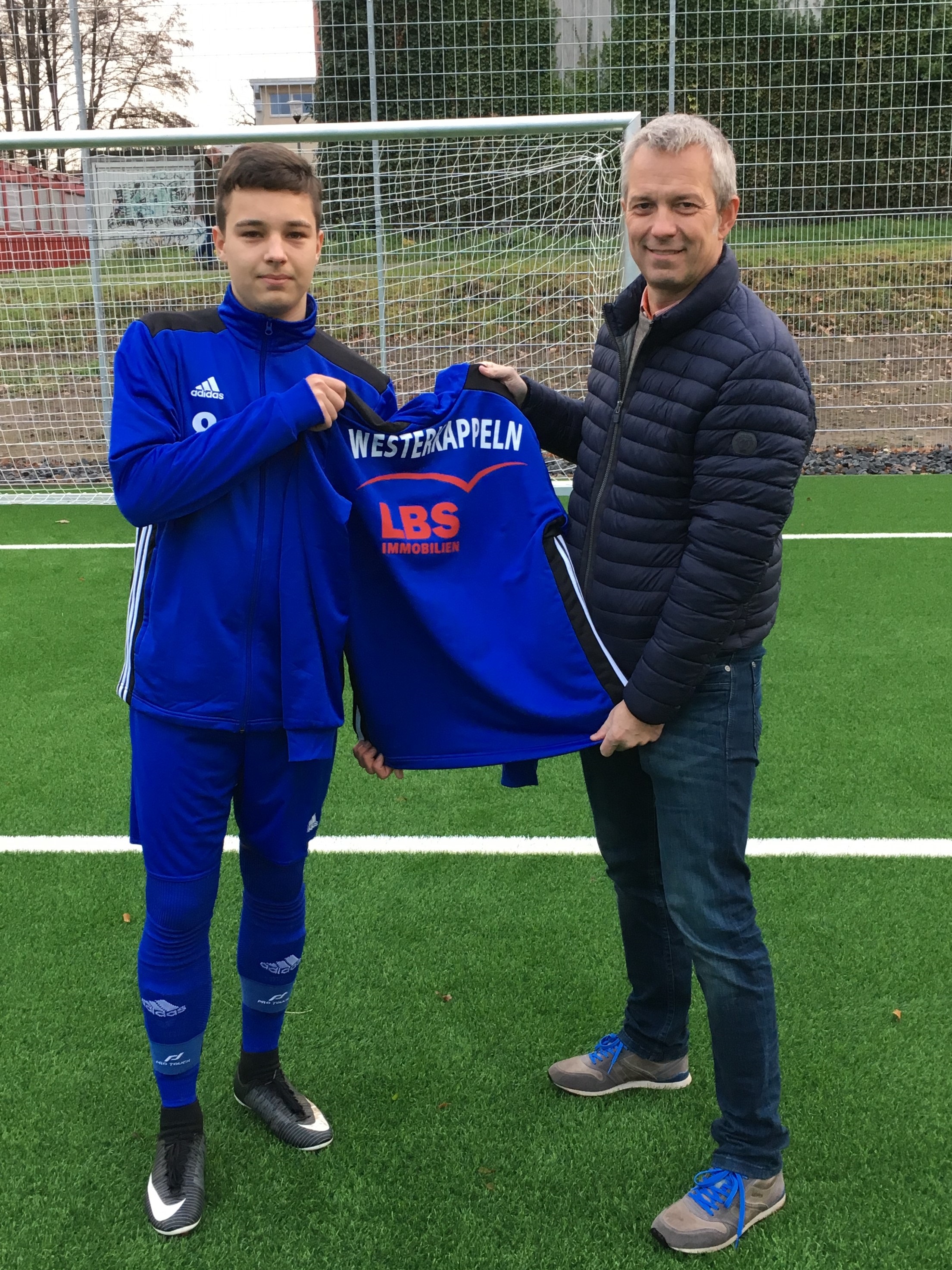 Hier übergibt Michael Hüsken offiziell die neuen Trainingsanzüge an unseren Kapitän Maris Löbel.